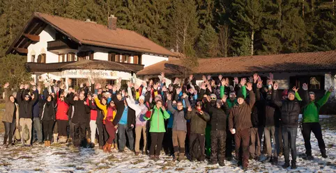 Gruppenfoto der Mitarbeitenden im Schnee vor einer Berghütte im Rahmen einer Team Reise